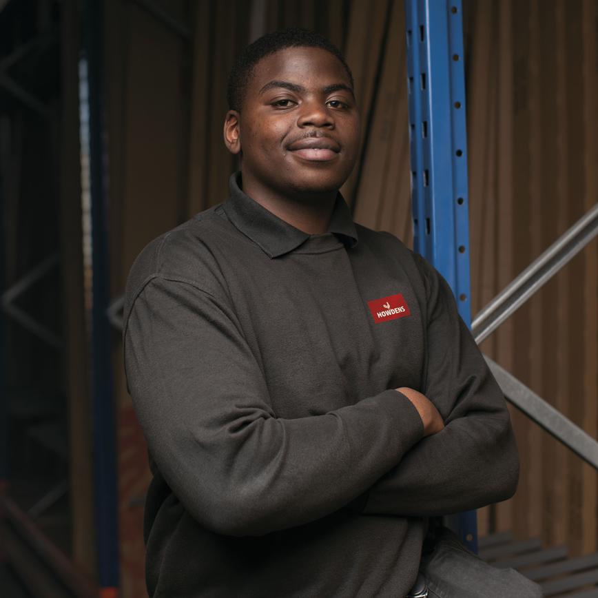 Image of an apprentice warehouse worker, standing in the depot smiling at the camera