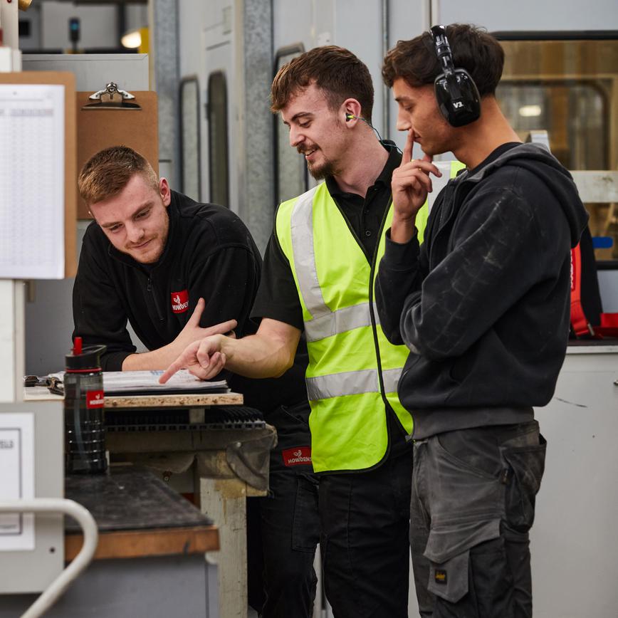 Image of three engineers looking at a plan on a table