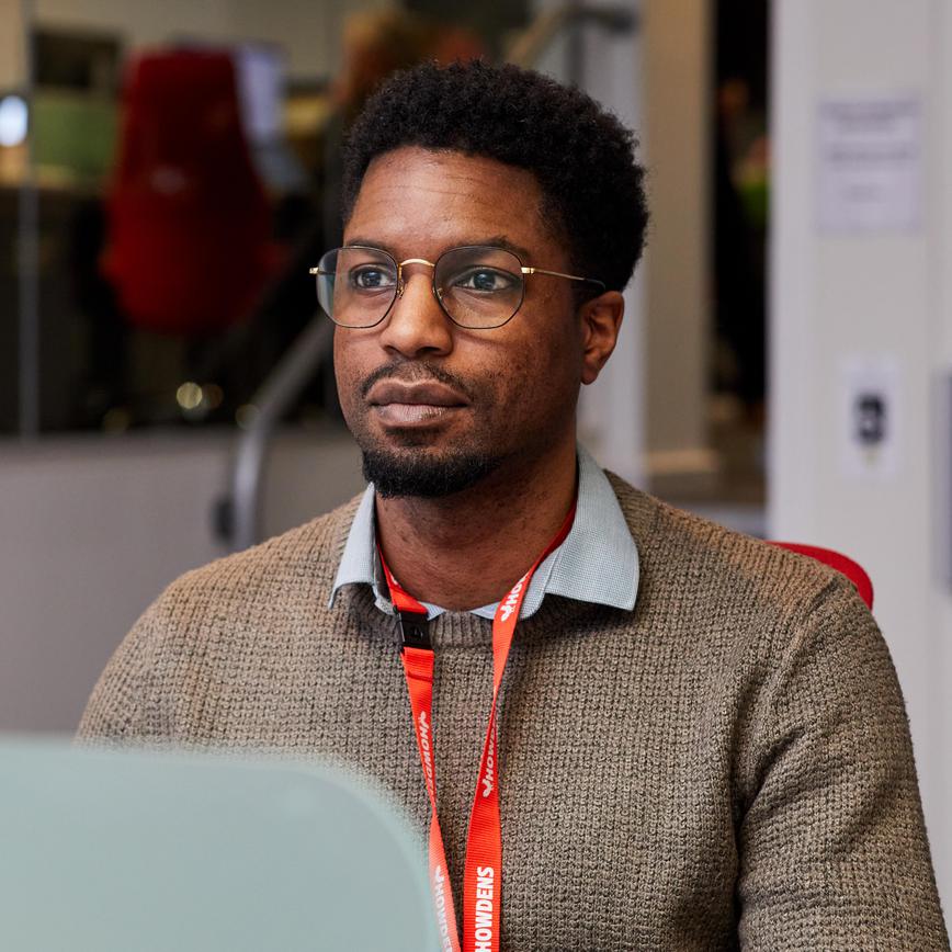 Man sat at desk with glasses on, looking at his computer screen