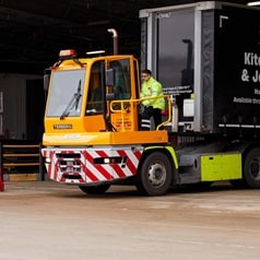 Man climbing into the front loader of a Howdens Truck