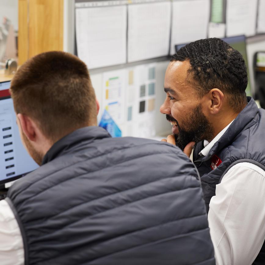 Two members of Howdens staff, sat in an office looking at online learning and development material.