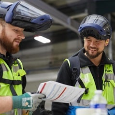 Two employees in the operations department at a Howdens manufacturing facility. They are wearing protective facewear.