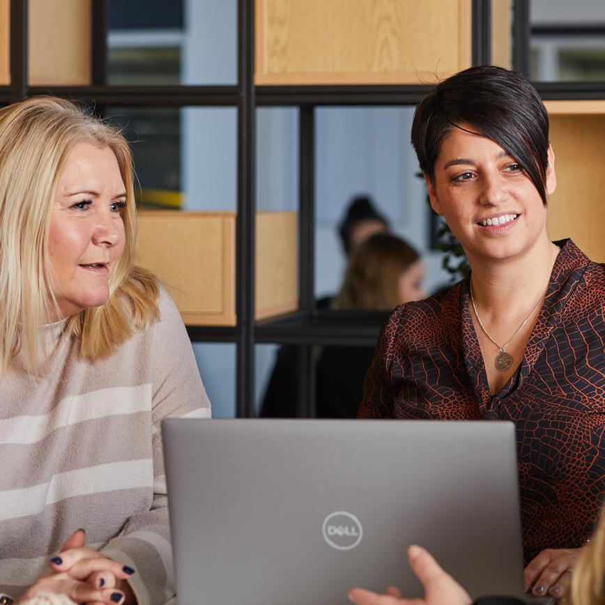 A group of staff in the fleet and facilities team, part of the support department, sat meeting at a desk around a laptop.